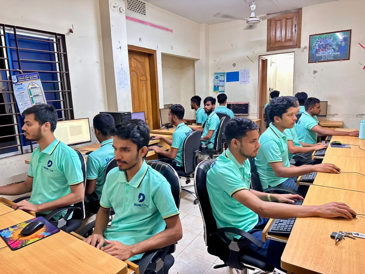Team members in Dreams IT Park polo shirts working at their computers
