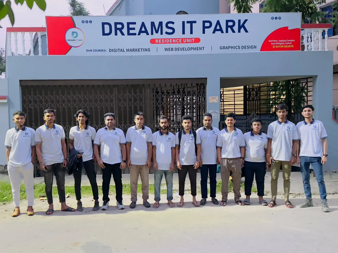 The team in Dreams IT Park polo shirts in front of the office signboard